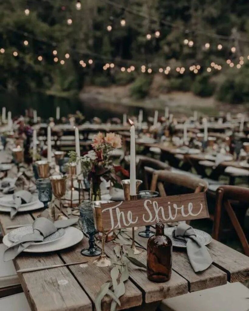 A rustic outdoor wedding table setting featuring a wooden sign that reads The Shire.
